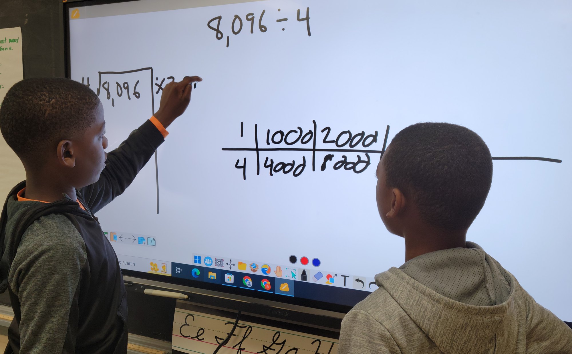 Two fourth graders working a division problem at the board