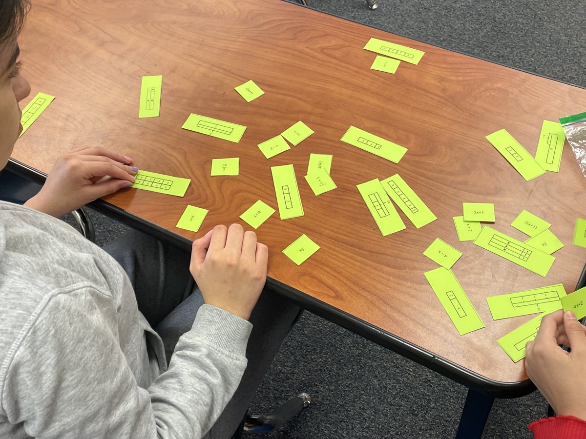 A 4th grader matching fraction bar cards on her desk