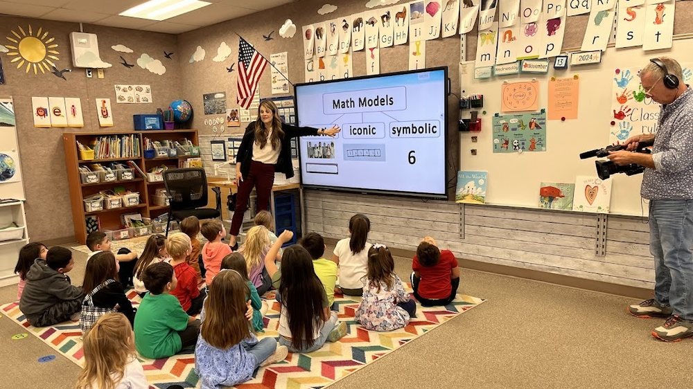 A DMTI math lesson in progress — teacher at the board, students on the carpet