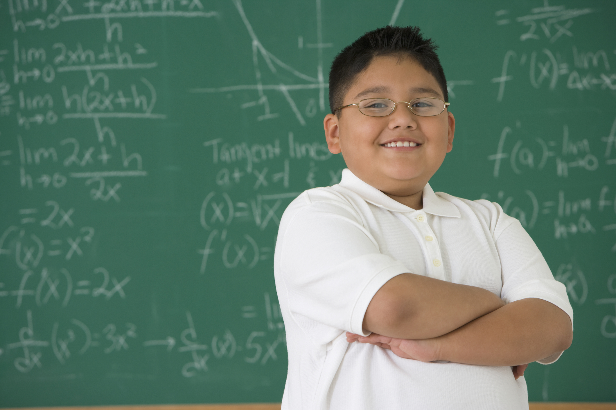 Hispanic elementary student solving math problems at blackboard